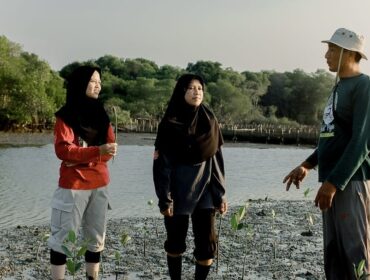 Ketua Kelompok Mangrove Sidodadi Maju, Wachana Ari Purwanto bersama dua pemuda tengah menanam bibit mangrove di Pantai Desa Pasarbanggi, Rembang, baru-baru ini. (Foto: rembangsepekan.com)